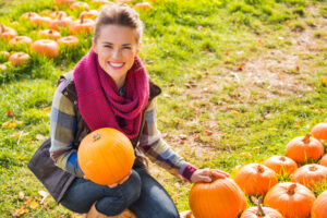 Portrait,Of,Smiling,Beautiful,Woman,Holding,Pumpkins,On,The,Pumpkin